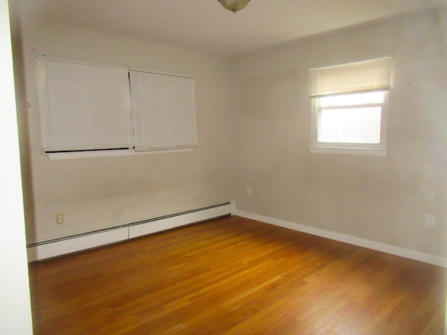 unfurnished room featuring wood finished floors, baseboards, and a baseboard radiator