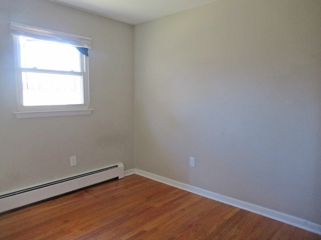 unfurnished room featuring wood finished floors, baseboards, and baseboard heating