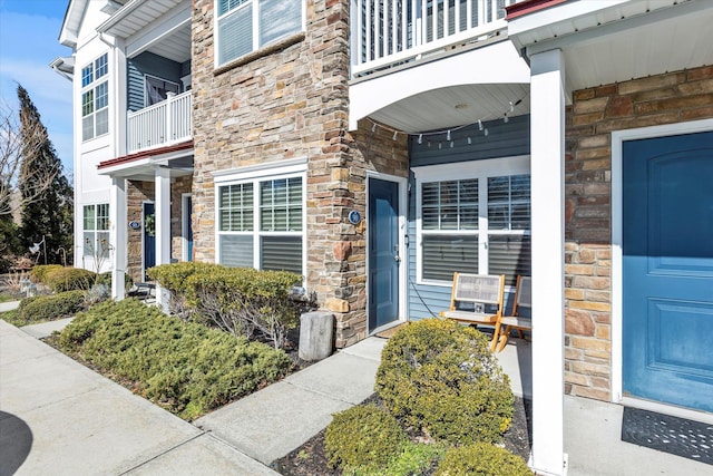 view of exterior entry featuring a porch and stone siding