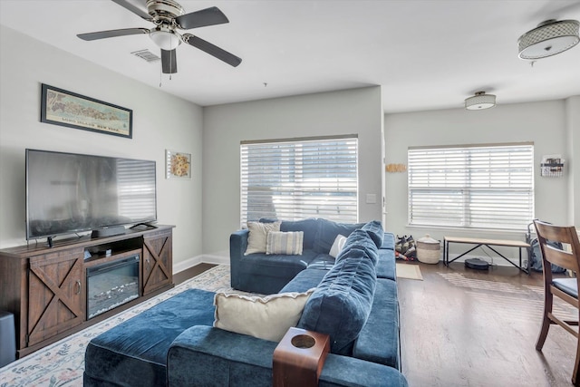 living area with ceiling fan, visible vents, baseboards, and wood finished floors