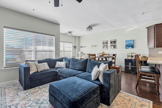 living area featuring a ceiling fan, light wood-type flooring, and baseboards