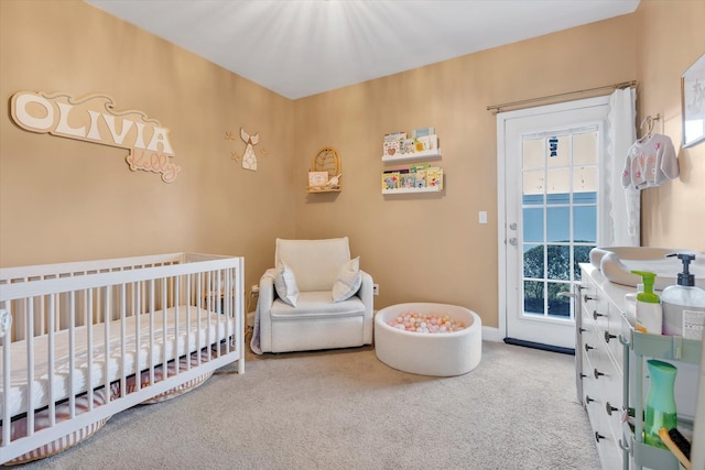 bedroom featuring baseboards, carpet floors, a nursery area, and access to exterior