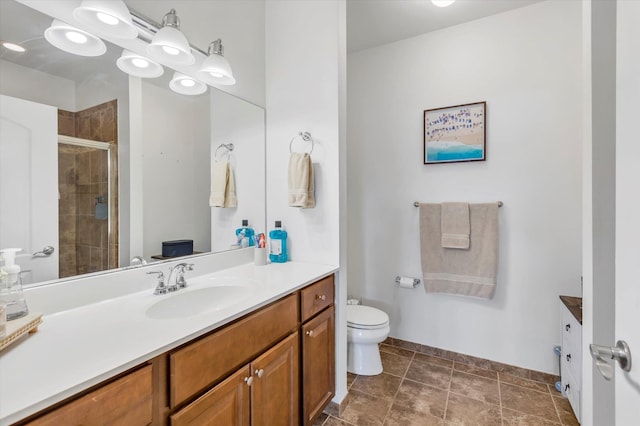 bathroom with baseboards, a shower stall, vanity, and toilet