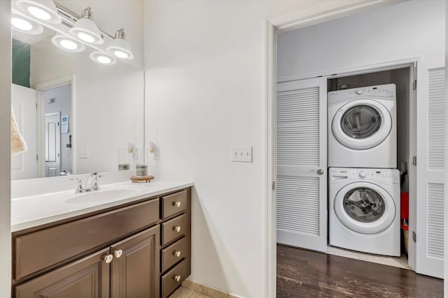 bathroom with stacked washing maching and dryer, vanity, and wood finished floors