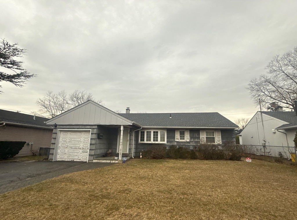 ranch-style house with aphalt driveway, an attached garage, a front yard, and fence