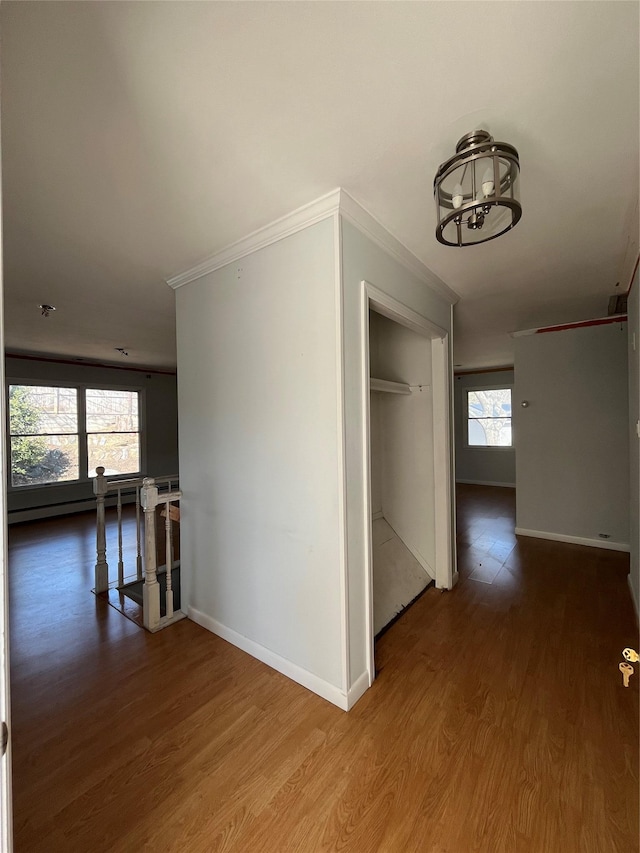 hall with wood finished floors, crown molding, an upstairs landing, and baseboards