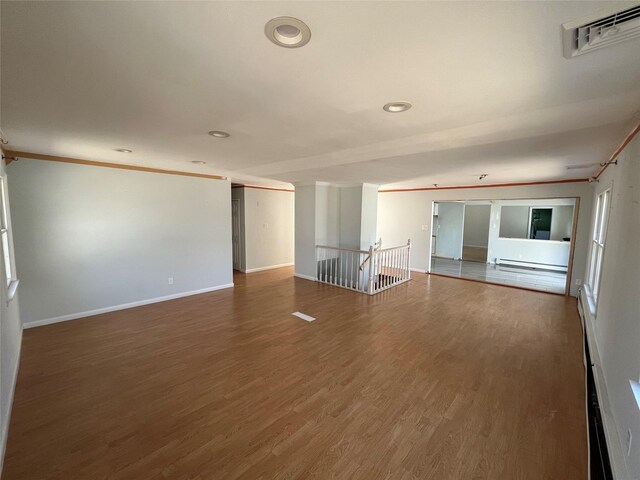 empty room with visible vents, baseboards, wood finished floors, and ornamental molding