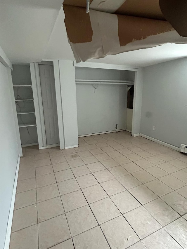 unfurnished bedroom featuring light tile patterned floors, baseboards, and vaulted ceiling