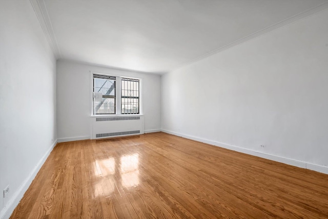 unfurnished room featuring ornamental molding, radiator heating unit, baseboards, and wood finished floors