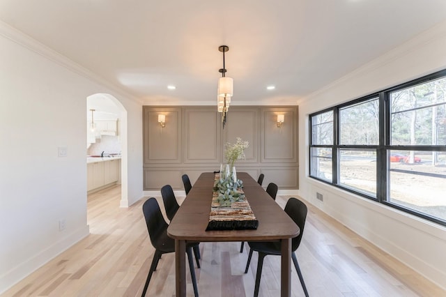 dining room featuring baseboards, recessed lighting, arched walkways, ornamental molding, and light wood-type flooring