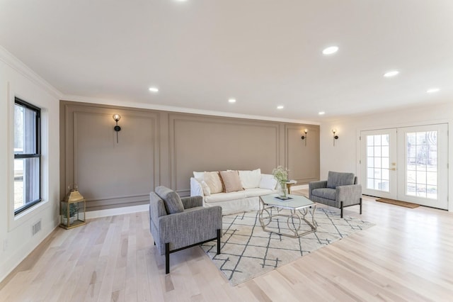 living area featuring a decorative wall, french doors, light wood-style floors, and a wealth of natural light