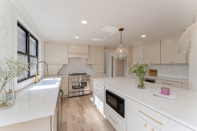 kitchen with a sink, stainless steel appliances, light countertops, pendant lighting, and tasteful backsplash