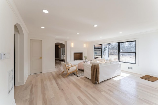 unfurnished living room with visible vents, arched walkways, and ornamental molding