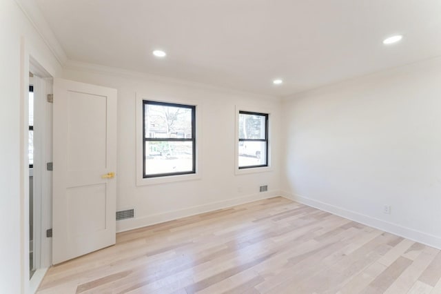 empty room featuring visible vents, light wood-type flooring, baseboards, and ornamental molding