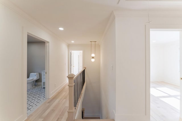 hallway featuring baseboards, light wood finished floors, recessed lighting, ornamental molding, and an upstairs landing