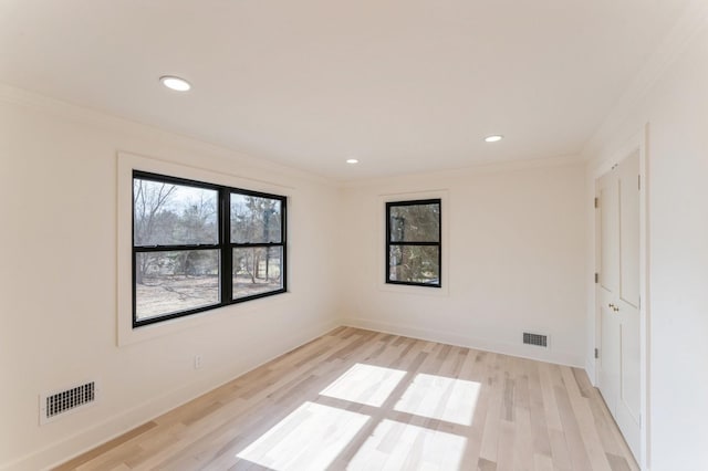 spare room featuring light wood finished floors, visible vents, and crown molding