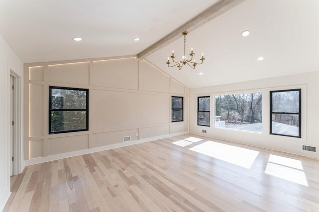 empty room with a decorative wall, vaulted ceiling with beams, light wood-style flooring, and visible vents