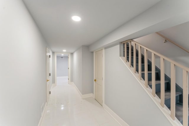 corridor featuring tile patterned floors, baseboards, recessed lighting, and stairs