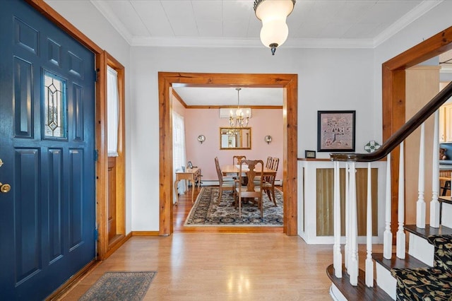 foyer with a notable chandelier, ornamental molding, wood finished floors, baseboards, and stairs