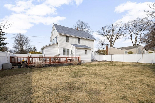 rear view of house with a deck, a lawn, a chimney, and a fenced backyard