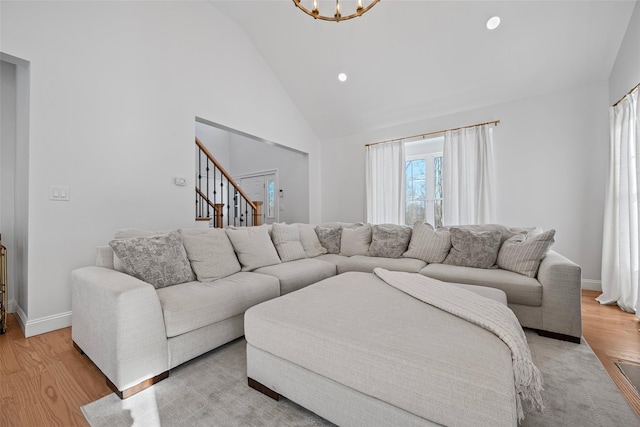 living area featuring baseboards, high vaulted ceiling, recessed lighting, light wood-style floors, and a chandelier