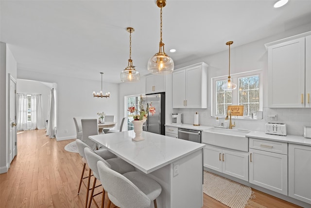 kitchen featuring a sink, light wood finished floors, backsplash, and stainless steel appliances