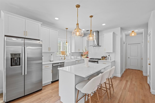 kitchen featuring wall chimney range hood, backsplash, appliances with stainless steel finishes, white cabinets, and light countertops