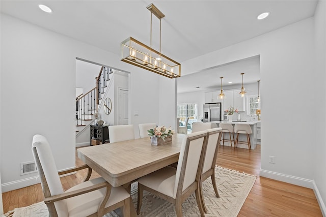 dining space with stairway, visible vents, light wood finished floors, baseboards, and recessed lighting