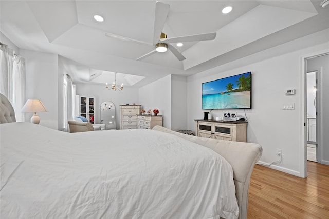 bedroom featuring a tray ceiling, recessed lighting, light wood-style floors, and baseboards