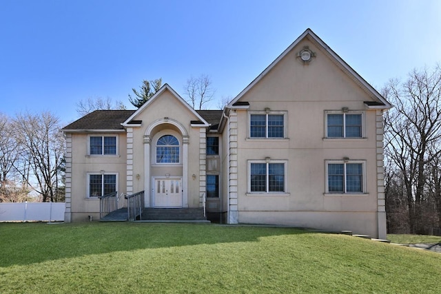 traditional-style home with stucco siding, fence, and a front lawn