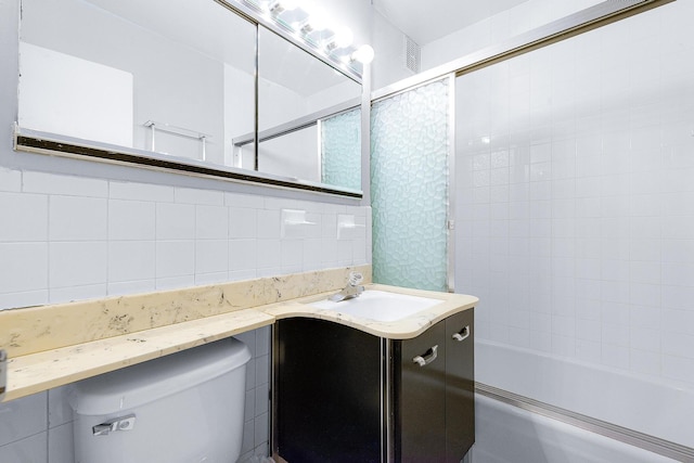 full bathroom with tasteful backsplash, tile walls, toilet, enclosed tub / shower combo, and vanity