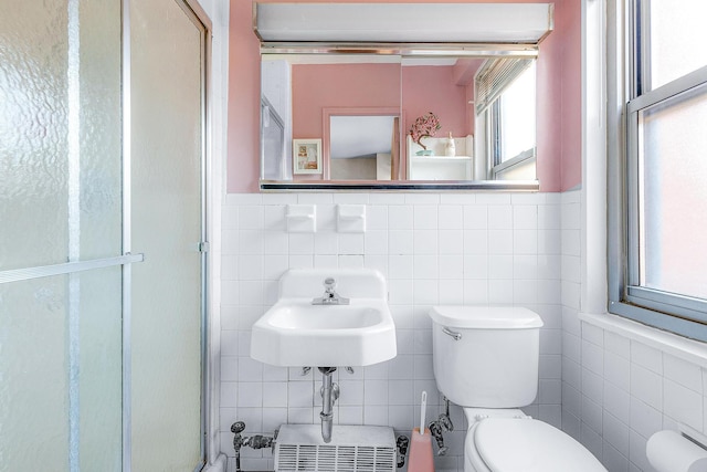 full bath with a shower stall, toilet, wainscoting, tile walls, and a sink