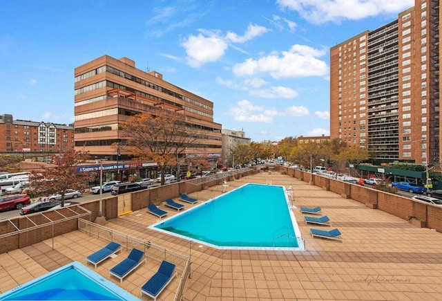 view of swimming pool featuring a view of city and fence