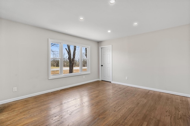 empty room featuring visible vents, recessed lighting, wood finished floors, and baseboards