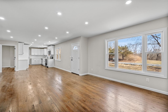 unfurnished living room featuring wood finished floors, recessed lighting, and baseboards