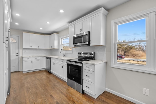 kitchen with decorative backsplash, dark wood-type flooring, appliances with stainless steel finishes, and a sink