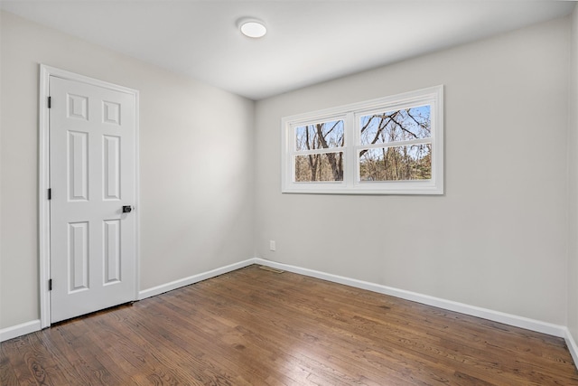 spare room with visible vents, wood finished floors, and baseboards