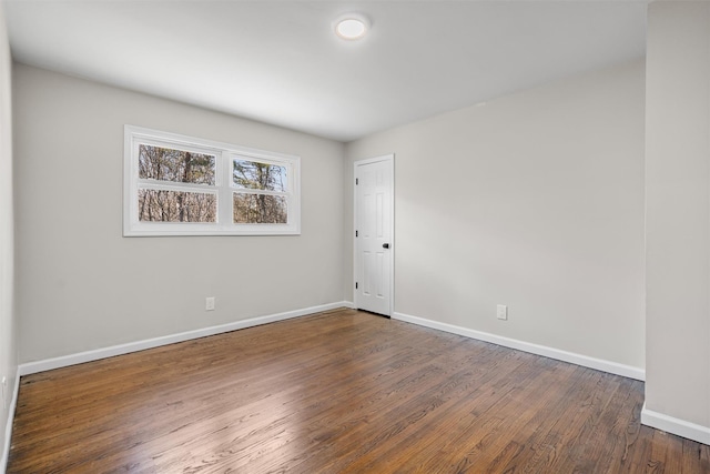 empty room with dark wood finished floors and baseboards