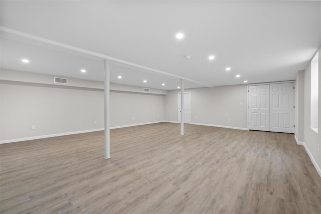 finished below grade area featuring recessed lighting, visible vents, light wood-style flooring, and baseboards