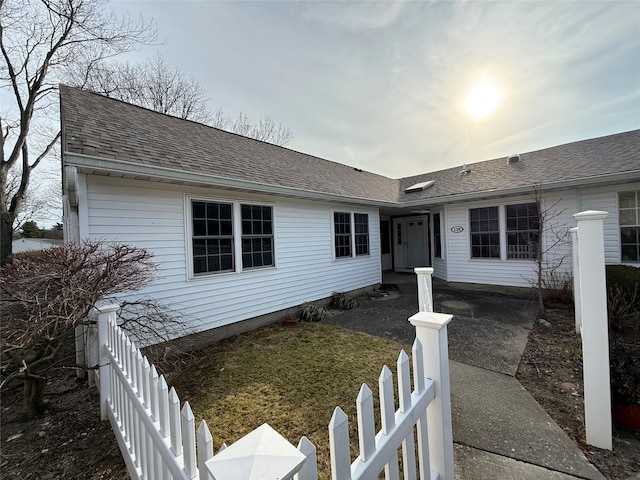 ranch-style home with fence and roof with shingles