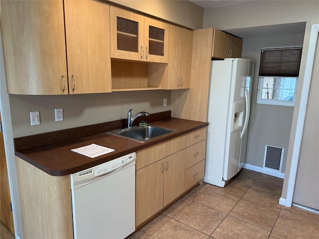 kitchen with a sink, white appliances, dark countertops, and light brown cabinets