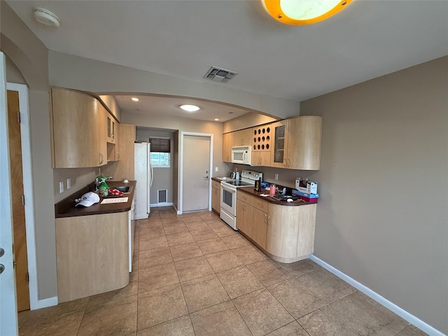 kitchen featuring visible vents, white appliances, dark countertops, and light brown cabinets