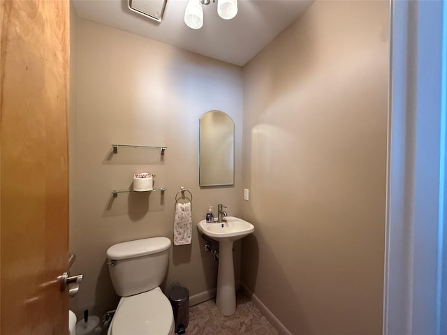 half bath featuring a sink, baseboards, and toilet