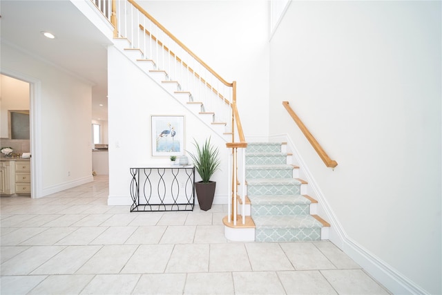 stairs featuring recessed lighting, crown molding, tile patterned flooring, baseboards, and a towering ceiling