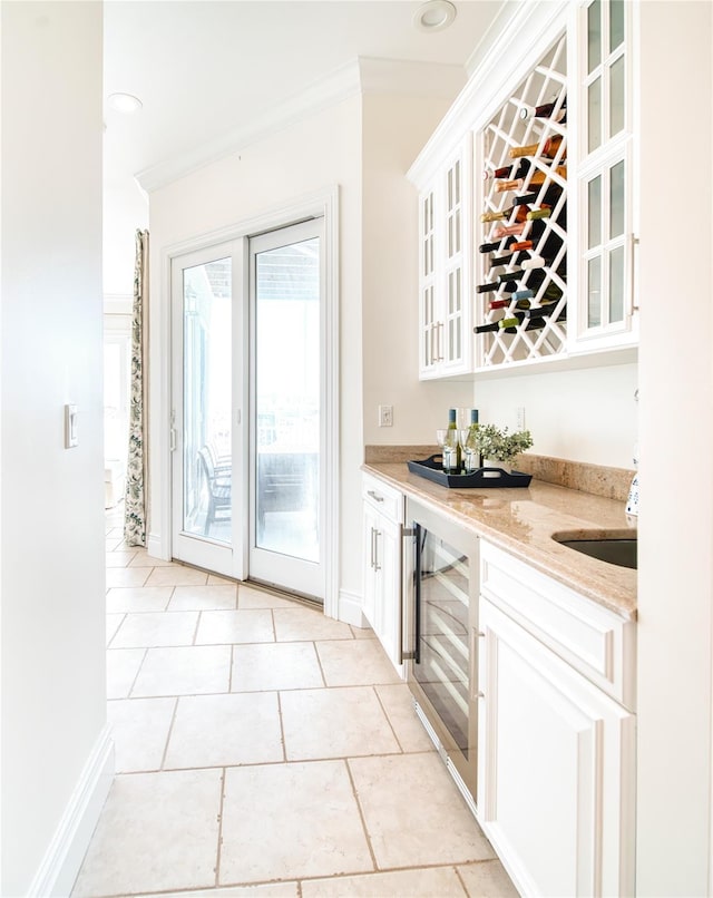 bar with wine cooler, a bar, baseboards, and ornamental molding