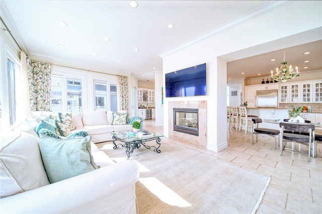 living room featuring an inviting chandelier, crown molding, recessed lighting, and a fireplace