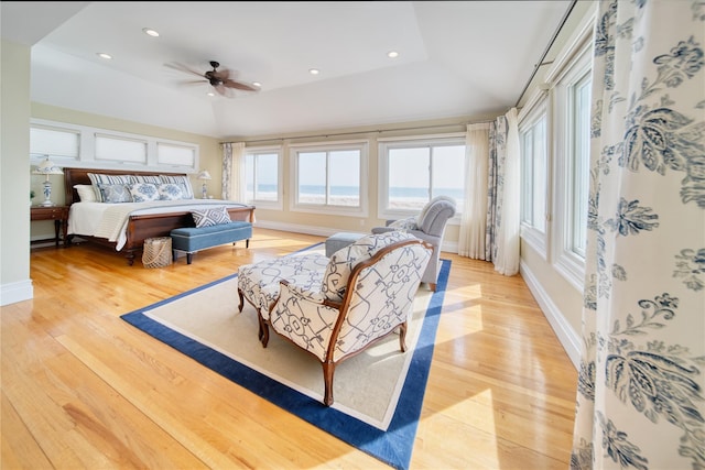 bedroom featuring light wood finished floors, recessed lighting, a tray ceiling, and baseboards