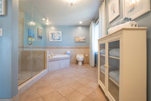 full bath with a wainscoted wall, tile patterned flooring, a shower stall, a garden tub, and toilet