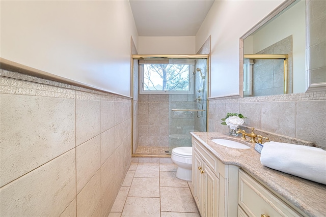 bathroom with vanity, tile walls, toilet, and a shower stall