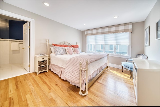 bedroom with ensuite bath, recessed lighting, baseboards, and light wood finished floors